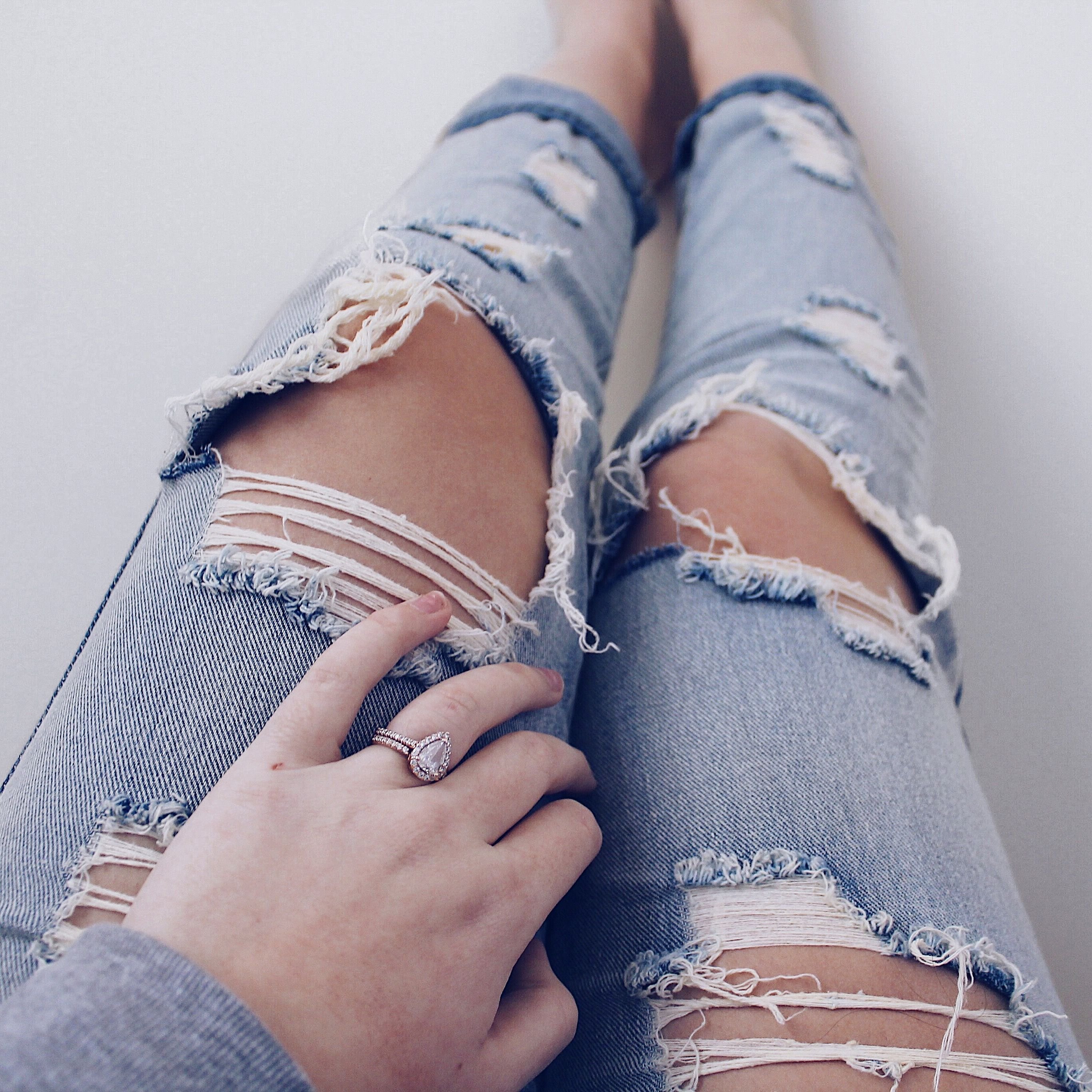 В одной руке джул. Женские ноги в джинсах. Ноги в рваных джинсах. Девушка в рваных джинсах. Женские ноги в рваных джинсах.